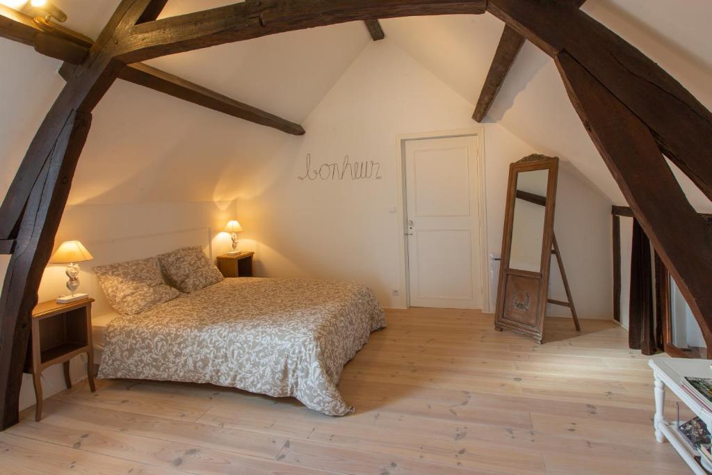 een slaapkamer op zolder met een bed en een spiegel bij Couette & Confitures in Nojeon-le-Sec