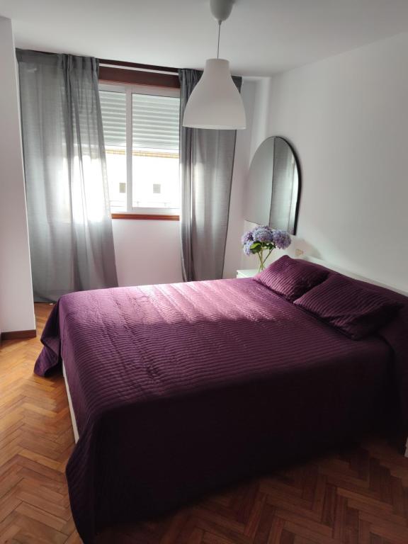 Schlafzimmer mit einem lila Bett und einem Spiegel in der Unterkunft Apartamento Julia in Vilagarcia de Arousa