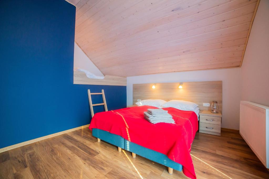 - une chambre avec un lit rouge et des murs bleus dans l'établissement Rellim Apartamenty, à Władysławowo