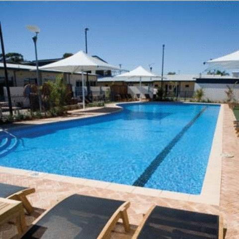 傑拉爾頓的住宿－布羅德沃特水手度假酒店，一个带桌子和遮阳伞的大型蓝色游泳池