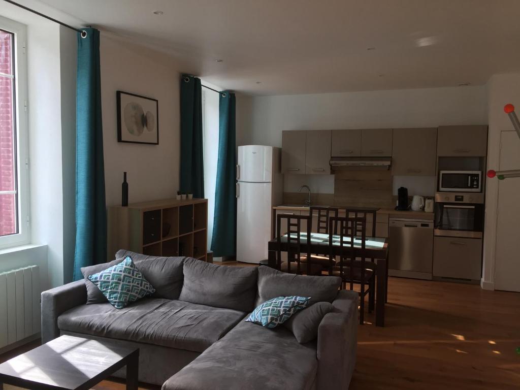 a living room with a couch and a kitchen at Magnifique et lumineux appartement au cœur du Sancy in Saint-Nectaire
