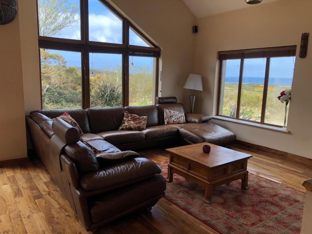 a living room with a leather couch and a coffee table at House with sea views close to Beach with WiFi and large kitchen and dining in Ardnagreevagh