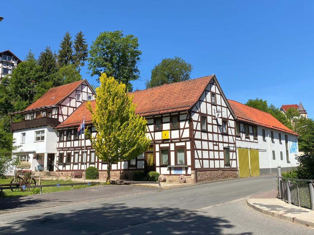 a building with a tree in front of a street at Hotel Pension Gelpkes Mühle in Bad Sachsa