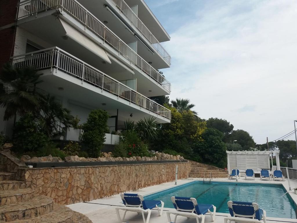 a swimming pool with chairs and a building at Panoramic 4 Apartments 2B in Castelldefels