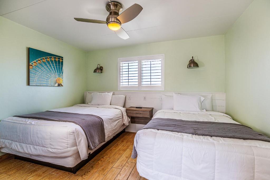 two beds in a room with a ceiling fan at Paradise Oceanfront Resort of Wildwood Crest in Wildwood Crest