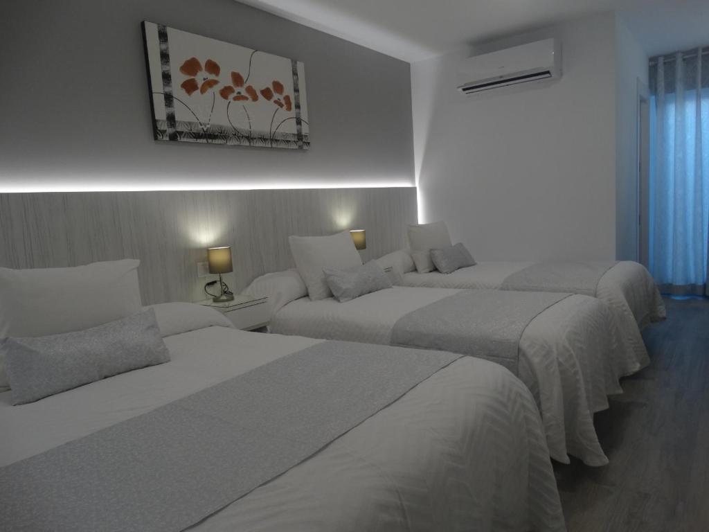 a hotel room with two beds and two lamps at Pensión mastil 16. P2 in Málaga