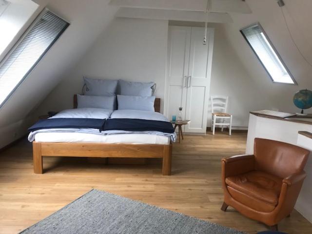 ein Schlafzimmer mit einem Bett und einem Stuhl im Dachgeschoss in der Unterkunft Moin ! in Timmendorfer Strand