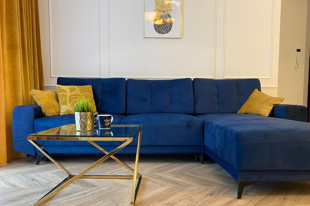ein blaues Sofa im Wohnzimmer mit einem Tisch in der Unterkunft CITYSTAY Św.Barbary Apartment in Danzig