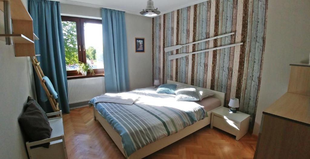a bedroom with a bed with blue curtains and a window at Gościrada in Darłowo