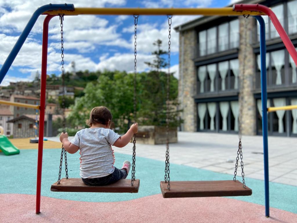 un niño sentado en un columpio en un parque infantil en Apartaments Turístics Cal Patoi, en Martinet