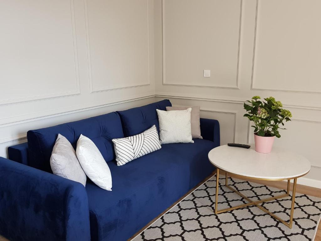 ein blaues Sofa mit weißen Kissen und einem Tisch in der Unterkunft Apartament Tarnovianka - Centrum in Tarnów
