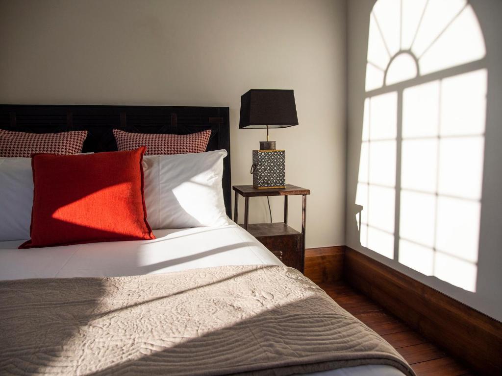 a bedroom with a bed with red pillows and a window at The Convent Hotel in Auckland