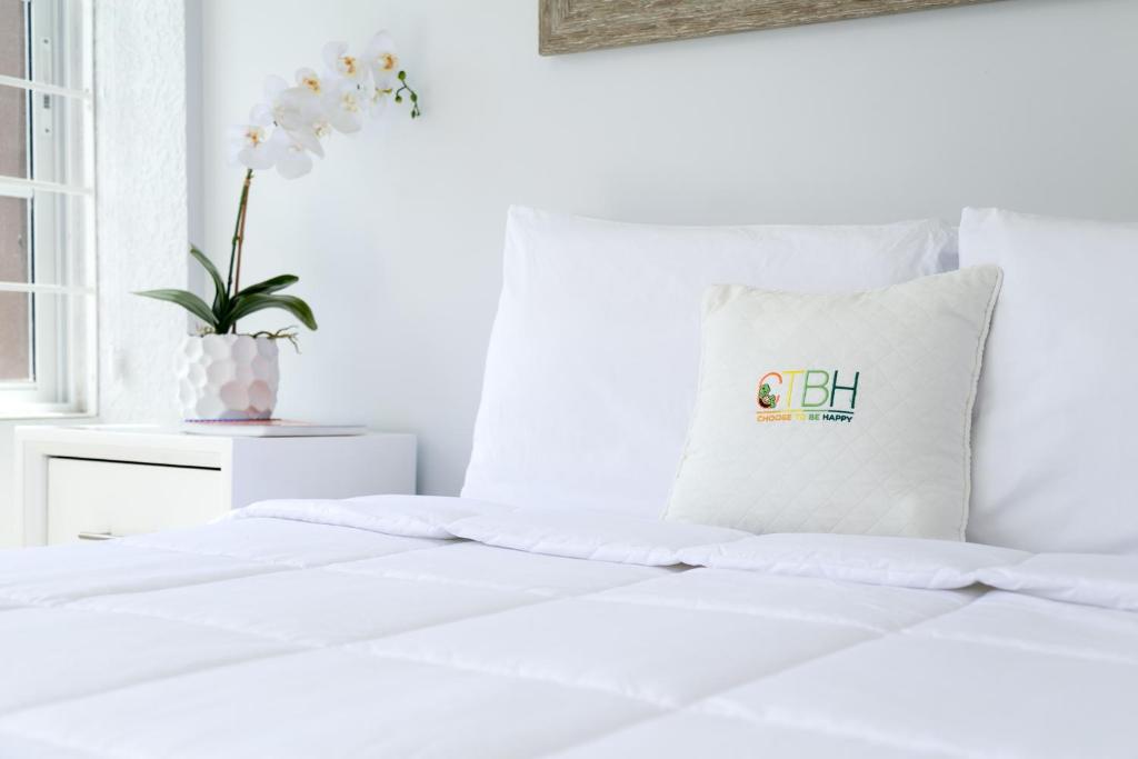 a white bedroom with a white bed with a pillow at Choose To Be Happy at Seymour # 9 and #16 - Studio Apartments in Kingston