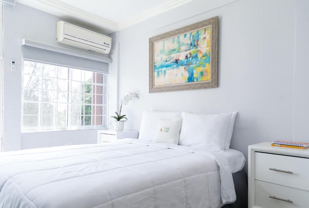 a white bedroom with a white bed and a window at Choose To Be Happy at Seymour # 9 and #16 - Studio Apartments in Kingston