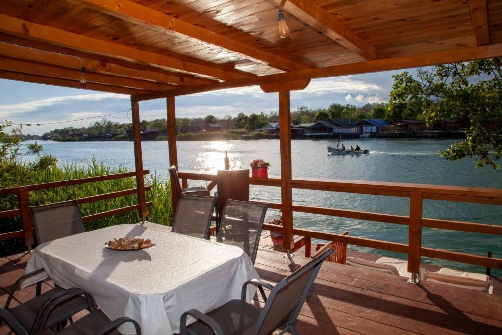 a table on a deck with a boat in the water at Cottage Ajna - Ada Bojana in Ulcinj