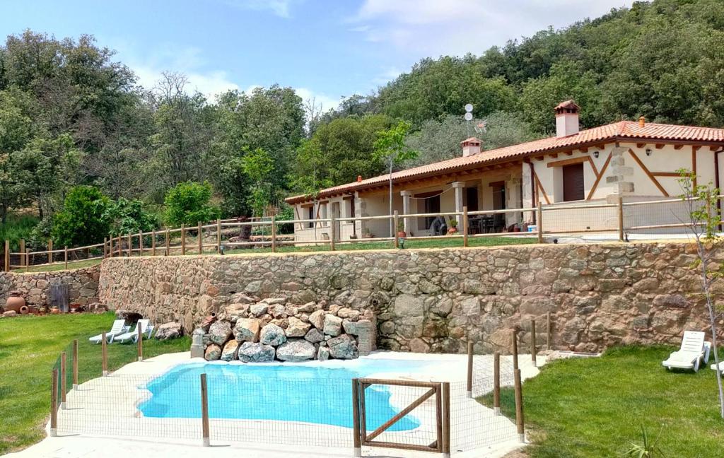 una casa con un muro in pietra e una piscina di Hotel Rural San Giles a Jarandilla de la Vera
