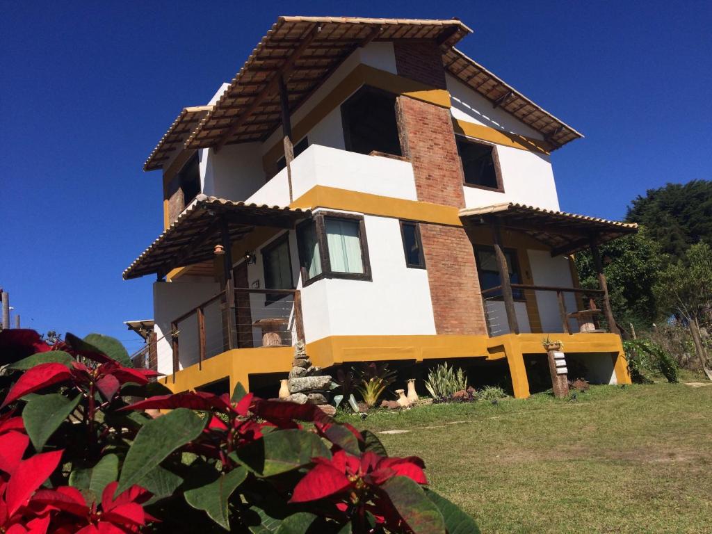 a house on a hill with red flowers in the foreground at Lavras Real in Lavras Novas