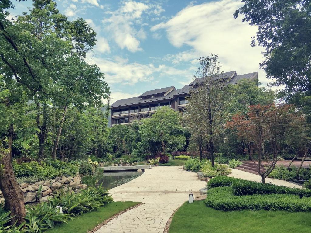 a building in the middle of a garden at New World Qingyuan Hotel -formerly KHOS QINGYUAN in Qingyuan