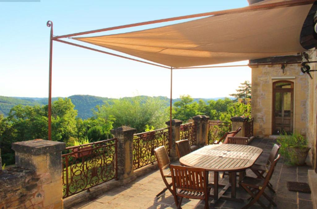 d'une terrasse avec une table et des chaises sur un balcon. dans l'établissement Maison de 4 chambres avec piscine partagee et jardin amenage a Saint Cybranet, à Saint-Cybranet