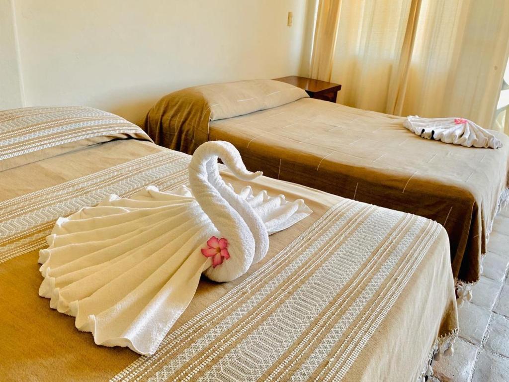 a swan decoration on two beds in a room at Hotel Cordelia's in Puerto &Aacute;ngel