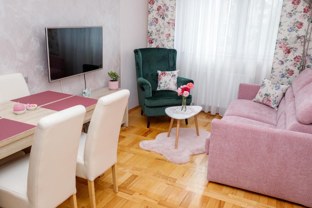 een woonkamer met een tafel en een roze bank bij Apartman Boska in Subotica