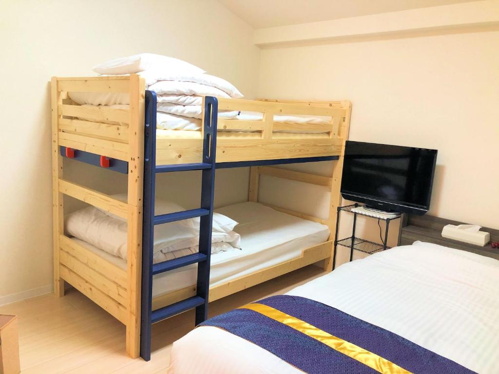 ein Schlafzimmer mit einem Etagenbett und einem TV in der Unterkunft COCOSTAY Matoba ココステイ マトバ in Hiroshima