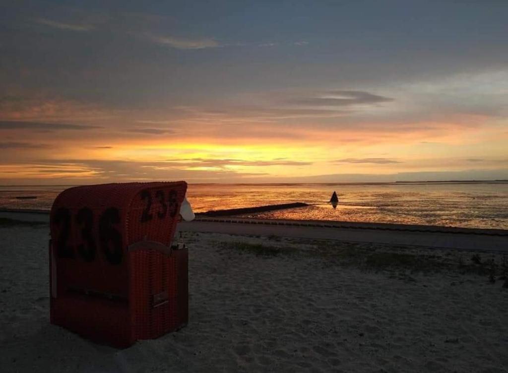 un cartel en la playa con una persona caminando por el océano en Fewo Haus Morgenstern im Ankerweg en Neuharlingersiel