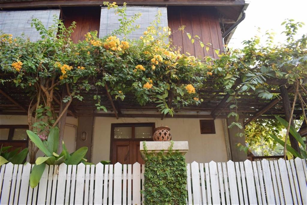 a house with a white fence and flowers on it at Sala Prabang Hotel in Luang Prabang