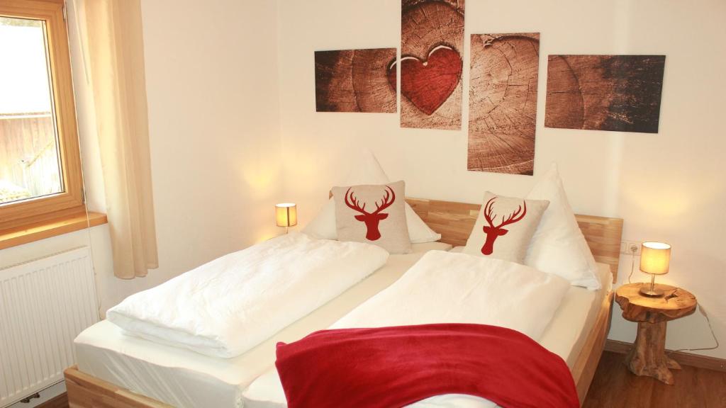 1 dormitorio con 1 cama blanca y 2 cruces en las almohadas en AllgäuBlick - Die Ferienwohnung, en Sonthofen