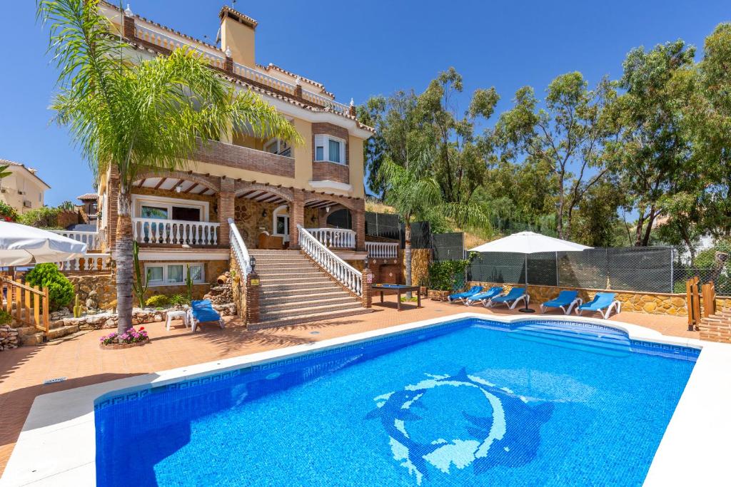 a villa with a swimming pool in front of a house at Villa Trebol in Mijas