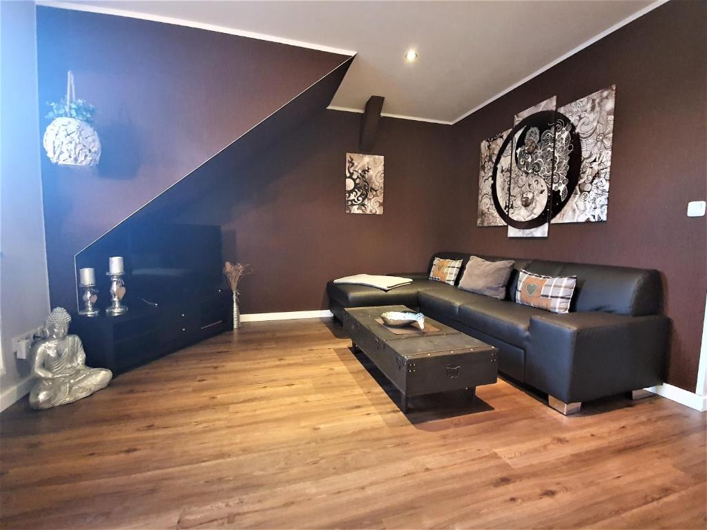 オストゼーバート・カールスハーゲンにあるFerienwohnung Jamieのリビングルーム(黒い革張りのソファ、階段付)