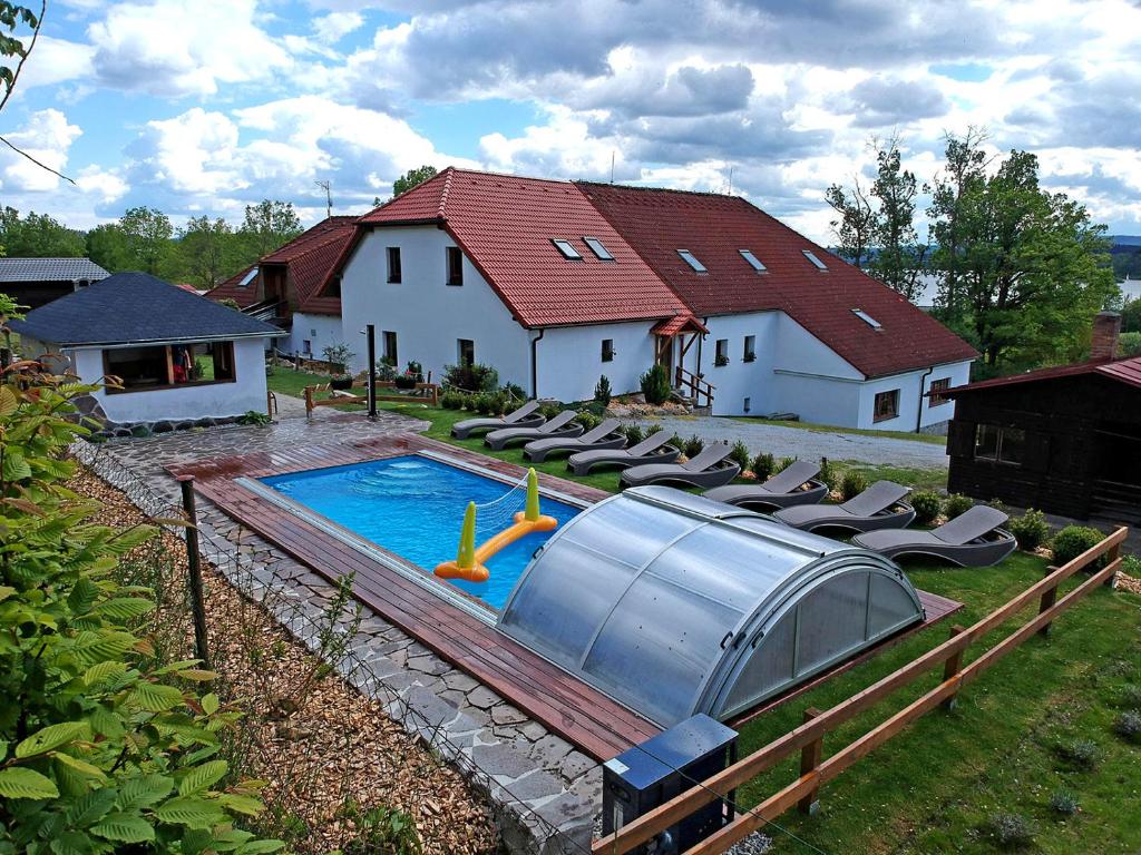 a house with a swimming pool with chairs around it at EDER- Penzion & Apartmány in Horní Planá