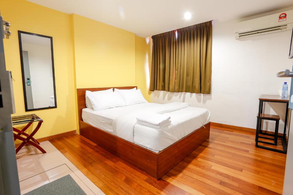 Lux Hotel في تيلوك إنتان: غرفة نوم بسرير وملاءات بيضاء ومرآة