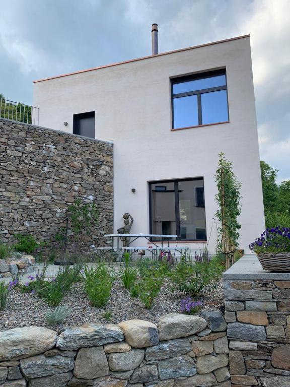 uma casa branca com uma parede de pedra e uma cerca de pedra em House of retreat Strada Vegia de Brén 9 em Breno