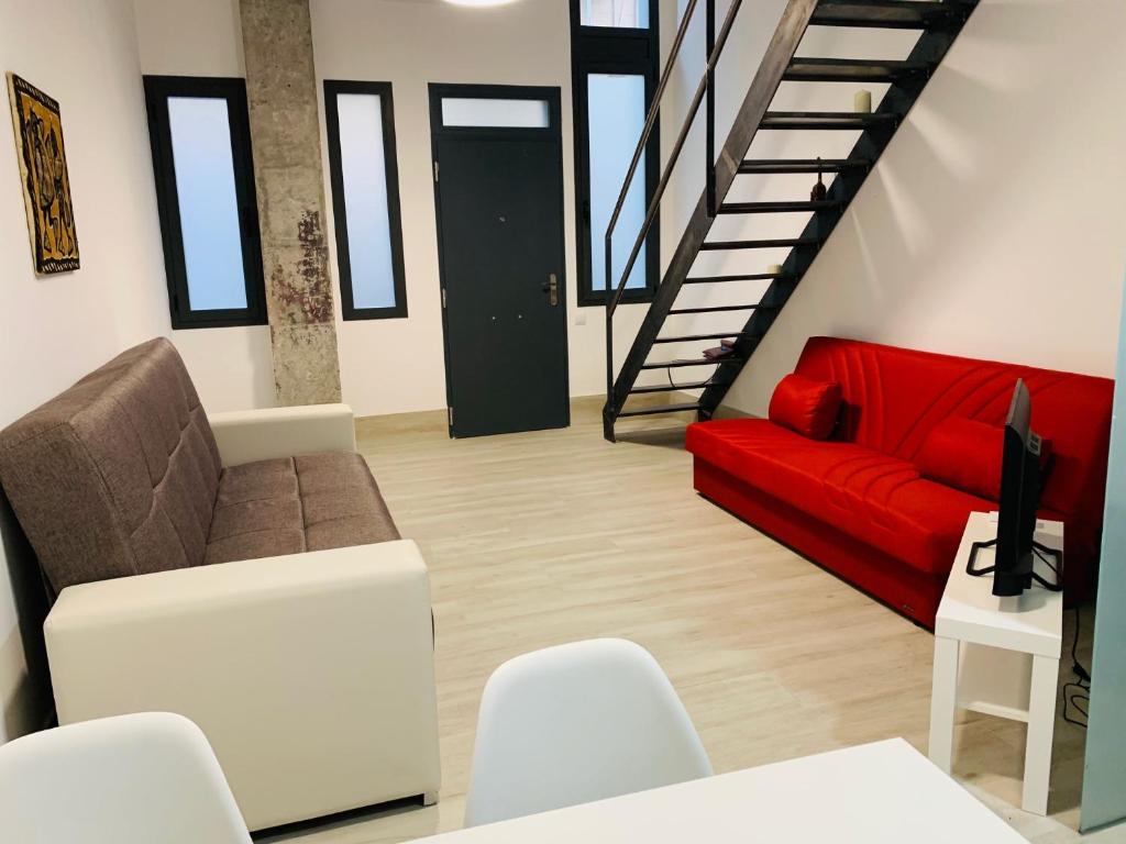 ein Wohnzimmer mit einem roten Sofa und einer Treppe in der Unterkunft NUEVOS DUPLEX PRINCIPE VERGARA in Madrid