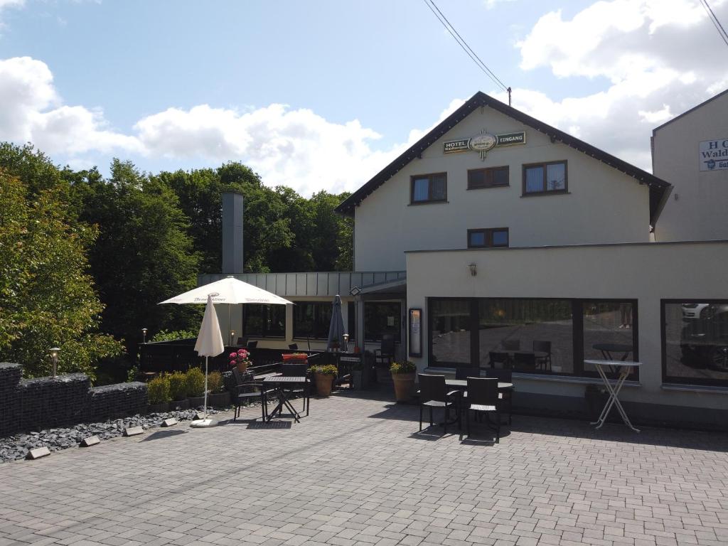 ein Gebäude mit einer Terrasse mit Tischen und einem Sonnenschirm in der Unterkunft Hotel Waldterrasse in Rengsdorf