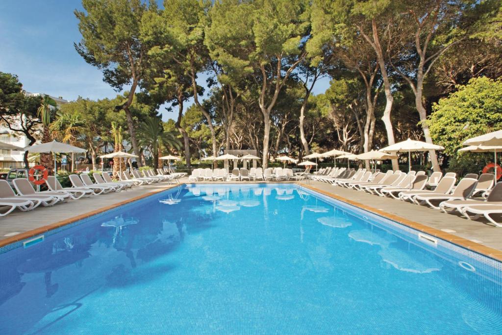 ein großer Pool mit Stühlen und Sonnenschirmen in der Unterkunft Hotel Riu Festival in Playa de Palma