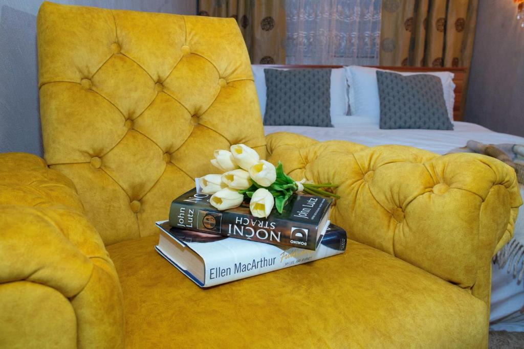 Una pila de libros sobre un sofá amarillo con flores. en TOPILCHE APARTMENT, en Ternopilʼ