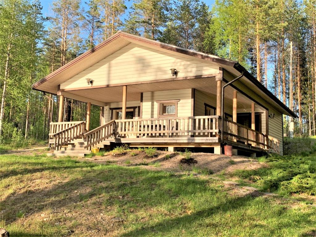 ein kleines Haus mit einer großen Veranda und einer Terrasse in der Unterkunft Lappalaisen lomamökit Mäntypirtti in Puumala