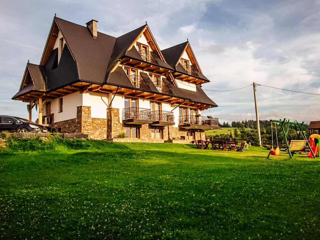 ein Haus auf einem grünen Feld mit einem Hof in der Unterkunft Góralski Przystanek dom dla max 17 osób in Biały Dunajec
