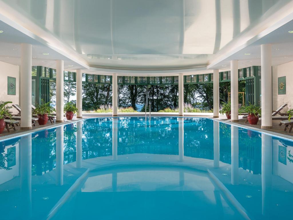 una piscina cubierta de agua azul en un edificio en Travel Charme Nordperd & Villen en Göhren