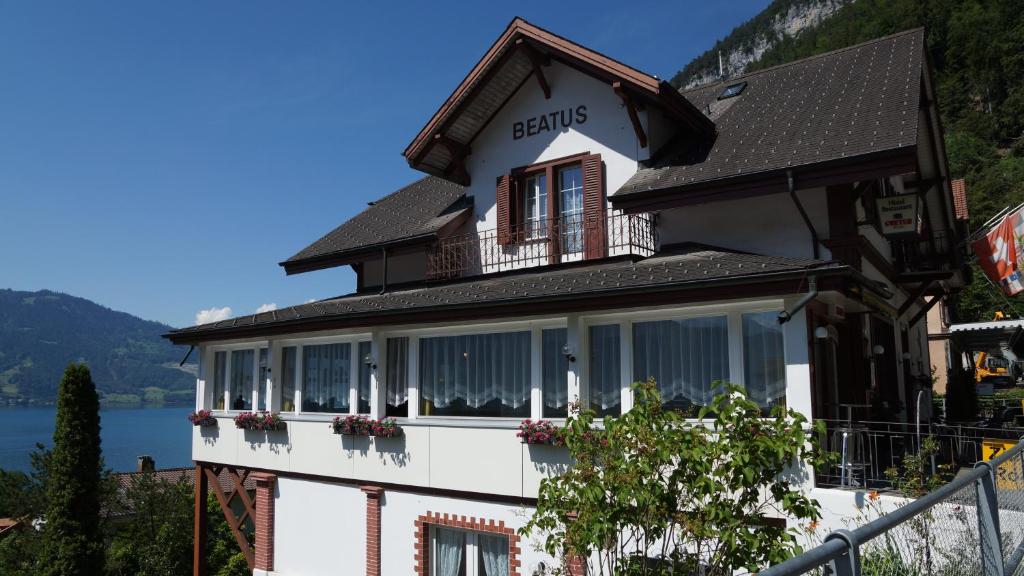 een wit gebouw met ramen en bloemen erop bij Hotel Beatus in Interlaken