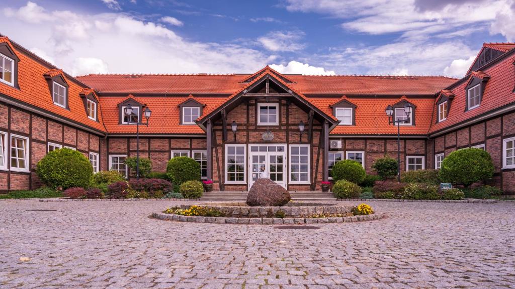 a large brick building with a courtyard in front of it at Hotel Habenda in Budzyń