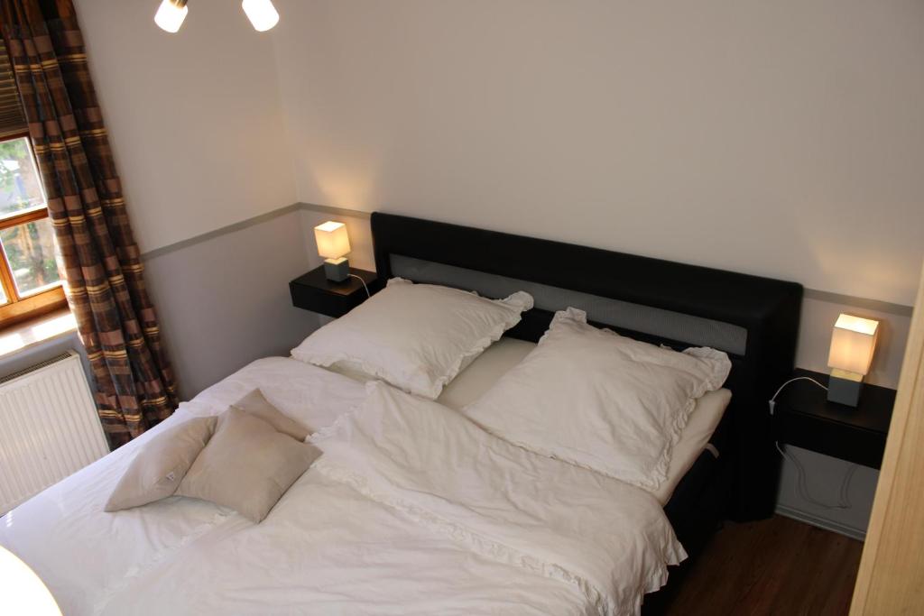 uma cama com lençóis brancos e almofadas num quarto em Ferienwohnung Martin em Eschwege