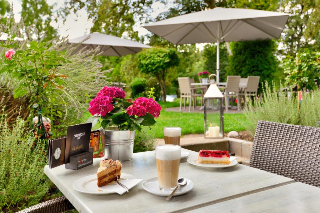 una mesa con dos platos de pastel y una taza de café en Ringhotel Zweibruecker Hof en Herdecke