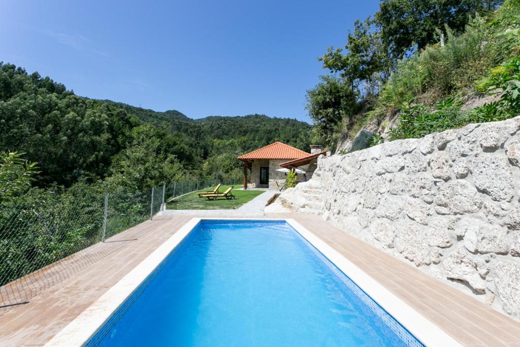 a swimming pool in front of a stone wall at Casa de Fundões - Gerês in Geres