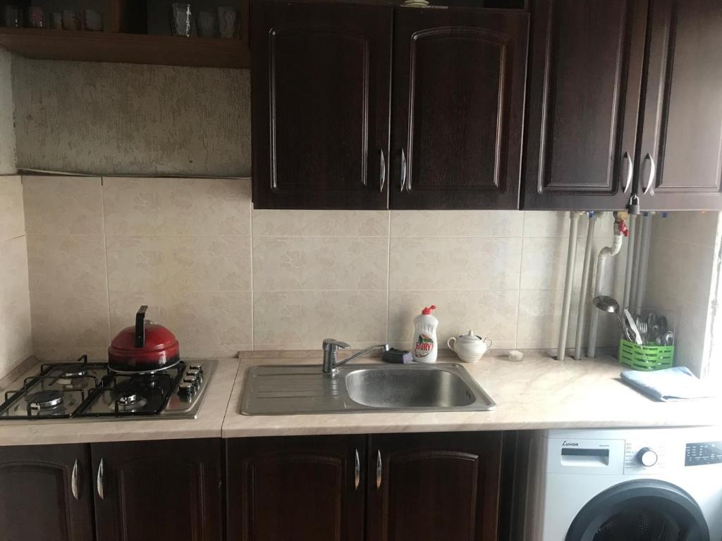 uma cozinha com um lavatório e um fogão em 2к Апартаменты возле ЖД вокзала и Академии 096-55-48-111 em Khmelʼnytsʼkyy