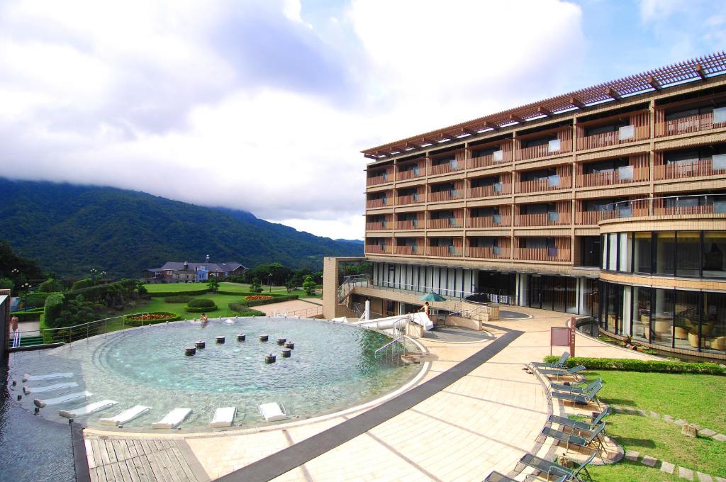 a hotel with a swimming pool in front of a building at Yang Ming Shan Tien Lai Resort &amp; Spa in Jinshan