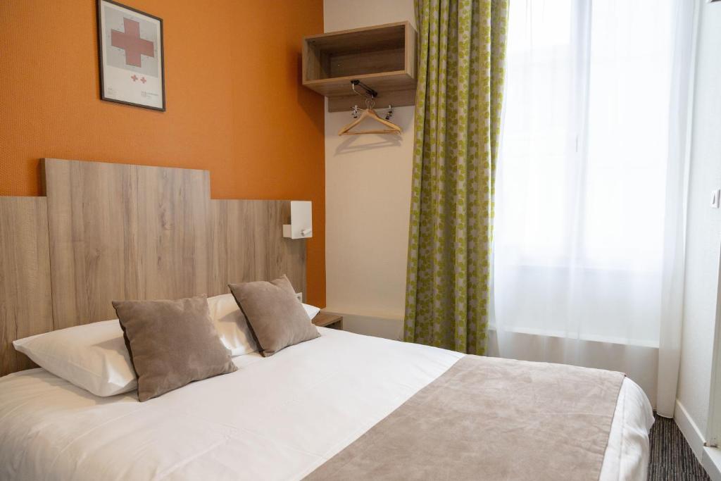 a bedroom with a white bed with orange walls and a window at Logis Hôtel Restaurant Lanex Amboise in Amboise