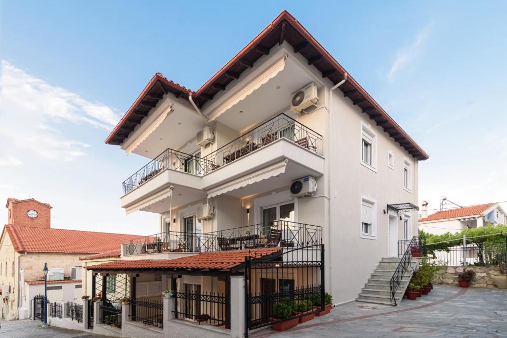 Un grand bâtiment blanc avec des balcons et des escaliers est à votre disposition. dans l'établissement Ariana Apartments, à Polychrono
